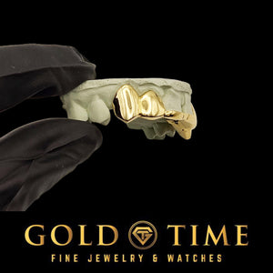 Yellow gold solid fang grillz on a cream dental model, angled view