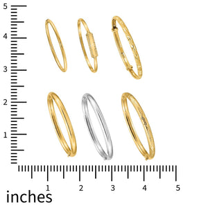 Six 14k gold baby bangles shown against an inch ruler for scale