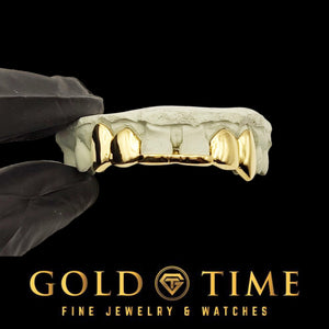 Yellow gold six piece solid grillz with pointed canine fangs, held in a gloved hand