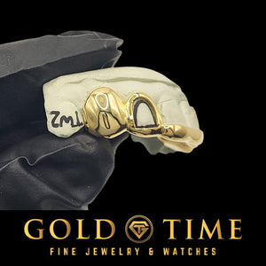 Side view of the open face lateral and solid canine cap on a marked dental mold held in a gloved hand, Gold Time