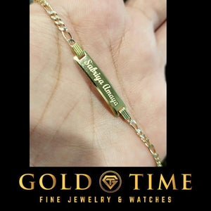 Hand holding a gold kids ID bracelet with an engraved nameplate