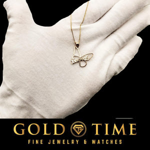Gold butterfly name pendant held in a white gloved hand