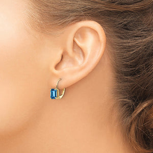 Close-up of an ear wearing a 14k gold leverback earring with a Swiss blue topaz emerald-cut stone