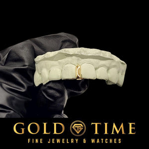 Yellow gold single gap grill on a mold held in a gloved hand