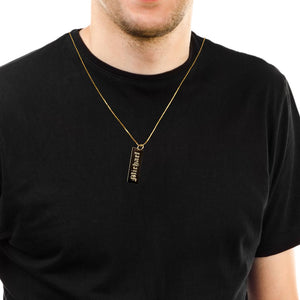 Man wearing a black enamel bar name charm on a gold chain over a black t-shirt