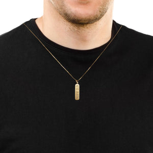 Man wearing a yellow gold vertical handwriting bar pendant on a thin chain over a black t-shirt