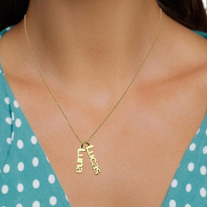 Woman wearing a gold two name vertical charm necklace reading Luna and Lucas
