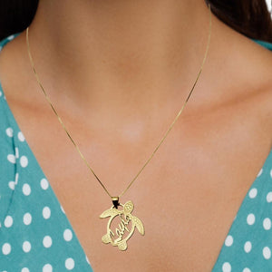 Gold sea turtle name pendant worn on a chain with a teal polka dot top