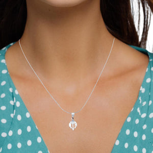 Woman in a teal polka dot top wearing the sterling silver monogram pendant on a fine chain