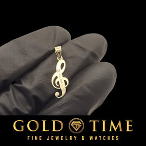 Yellow gold treble clef pendant with an engraved name, held between gloved fingers