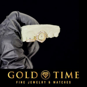Gloved hand holding a mold with a yellow gold iced open face canine and incisor tip double cap