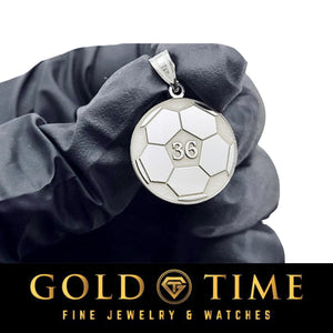 Gloved hand holding a white gold soccer pendant with the number 36