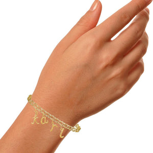 Wrist wearing a gold charm bracelet with lowercase script initial charms