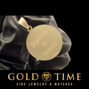 Gloved hand holding a basketball pendant with three lines engraved on the back