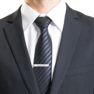 Man in a suit wearing an engraved sterling silver tie bar on a striped tie