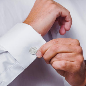 Engraved round monogram cuff link worn on a white French cuff