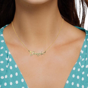Cross Luxe name necklace resting across a gloved hand, showing the cross built into the first letter