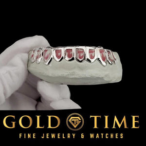 Silver open face grillz on a bottom dental mold held in a white-gloved hand