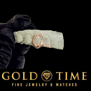 Rose gold open face fang and moissanite tip double cap grillz on a dental mold held in a gloved hand