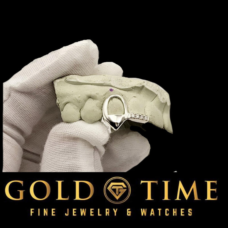 White gold open face fang double cap with moissanite incisor tip on a dental mold held in a gloved hand