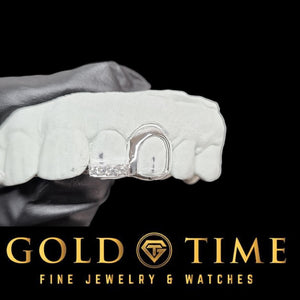 White gold open face canine grillz with iced moissanite tip on a mold held in a gloved hand