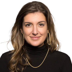 Woman wearing gold hoop earrings with a gold chain necklace