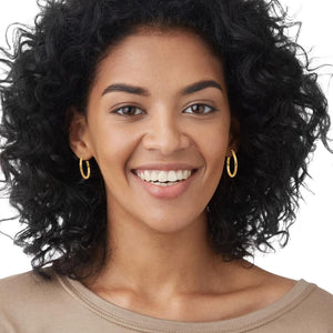 Woman wearing medium gold diamond cut hoop earrings