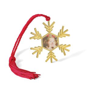 Gold plated snowflake photo ornament hanging from its red cord and tassel