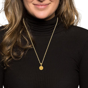 Woman wearing a small gold Saint Christopher medal on a chain