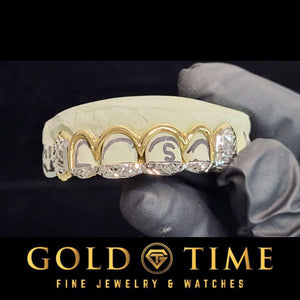 Gloved hand holding the top 6 of the two-tone set with yellow open windows, a diamond-cut tip bar and diamond-cut box canines