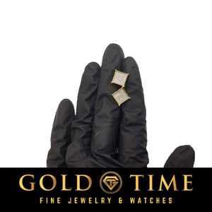 Yellow gold diamond square cluster studs on gloved fingertips for scale