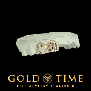 Double cap grill on a top mold with an open face canine and an open face incisor showing a cut-out letter B framed by moissanite, Gold Time logo