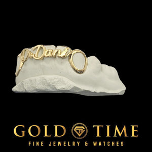 Angled view of a 6 piece gold name grillz set with cursive lettering spanning four front caps