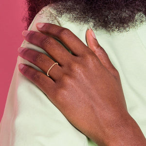 Close up of a hand resting on a shoulder wearing a dainty yellow gold twisted rope band