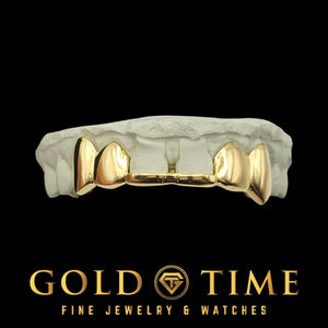 Yellow gold six piece solid grillz with fangs photographed against a black background