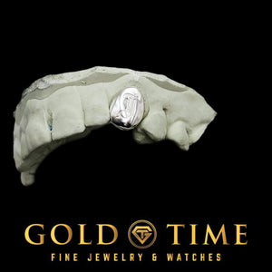 Polished single tooth cap with an engraved Old English letter on a dental mold, angled view