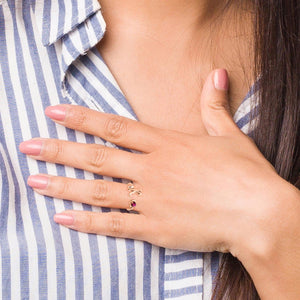 Woman in a striped shirt wearing an initial birthstone ring with her hand at her collar