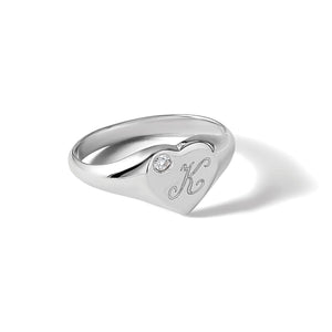 White gold diamond heart initial signet ring photographed at an angle on a white background