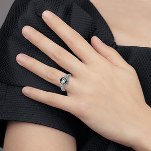 Woman's hand wearing the white metal floral monogram ring with black enamel face