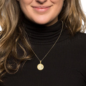 Woman wearing a small gold volleyball pendant on a thin chain