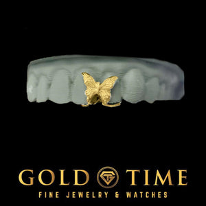Yellow gold butterfly gap grillz piece sitting between the front teeth of a grey dental model
