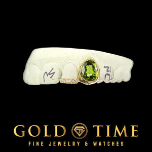 Gold double cap grill with a bezel-set green oval gem and a moissanite incisor tip on a dental mold