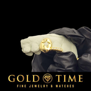 Gloved hand holding a mold with a yellow gold double cap grill featuring a star cutout and a moissanite tip