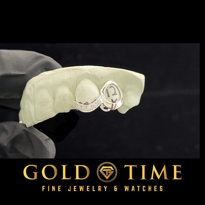 White double cap grillz with an open face canine and curved moissanite tip incisor, on a dental mold in a gloved hand
