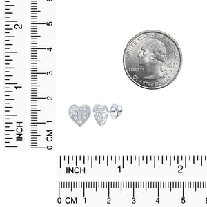White gold diamond heart studs beside a ruler and a quarter for scale