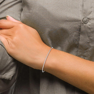 Wrist wearing a polished white gold bangle with a gray shirt