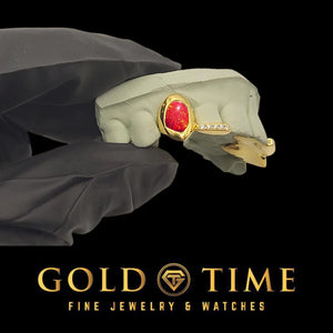 Yellow 2 piece grillz with a red oval galaxy enamel center and a moissanite tip on the next tooth, on a dental mold in a gloved hand