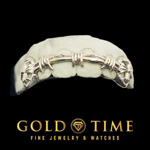 Barbed wire grill with cross cut-out canines on a dental mold, front view