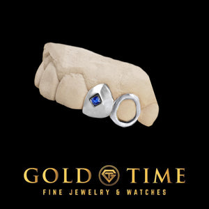 White silver double cap grillz on a dental mold: a solid cap set with a blue princess cut CZ beside an open face canine