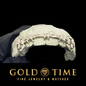 Barbed wire cross grill on a mold held in a black gloved hand